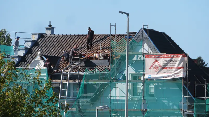 Dachdecker in Basel: Dachdecker arbeiten auf einem Steildach und verlegen Ziegel